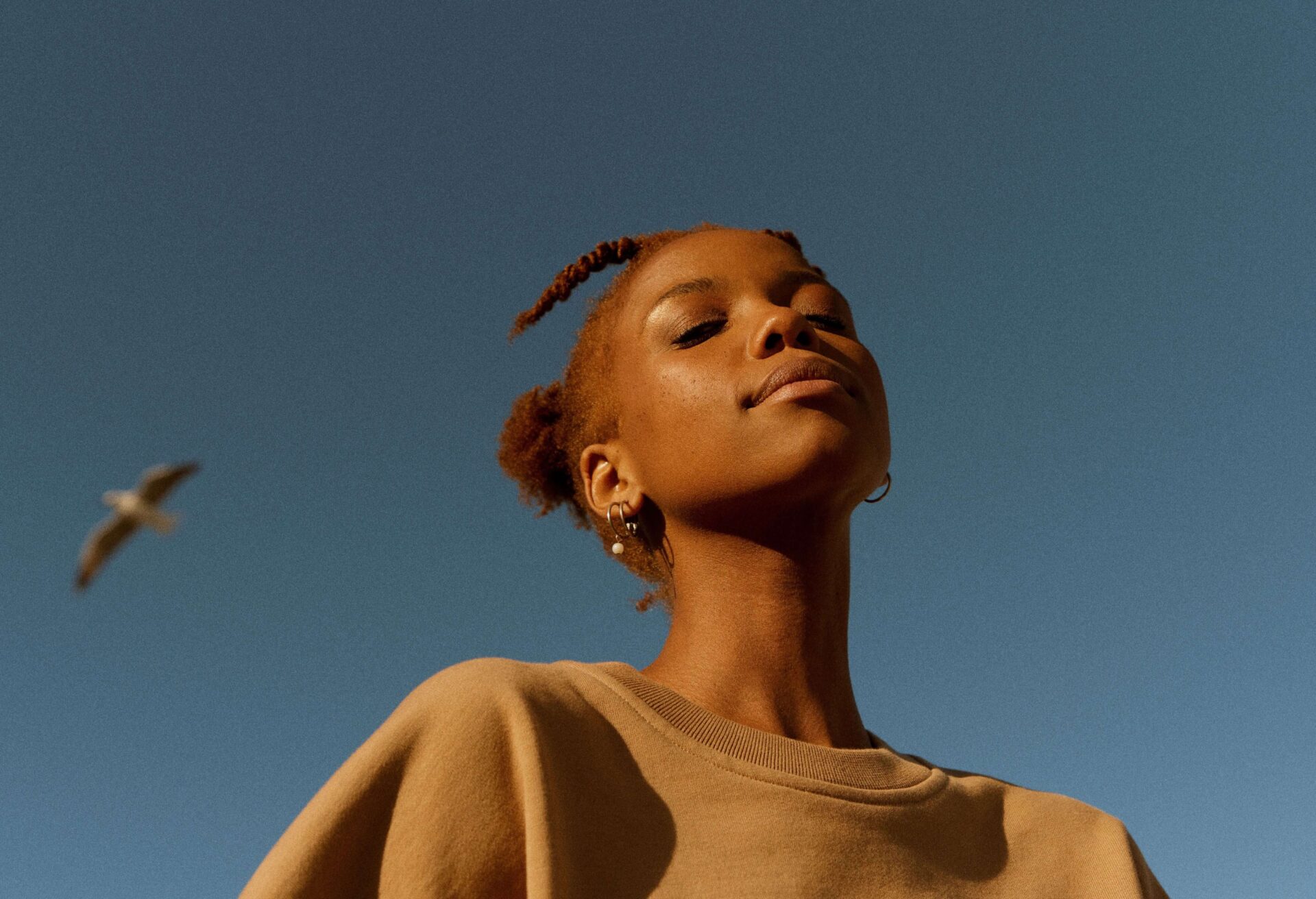 Image of a young person in front of a blue sky background.