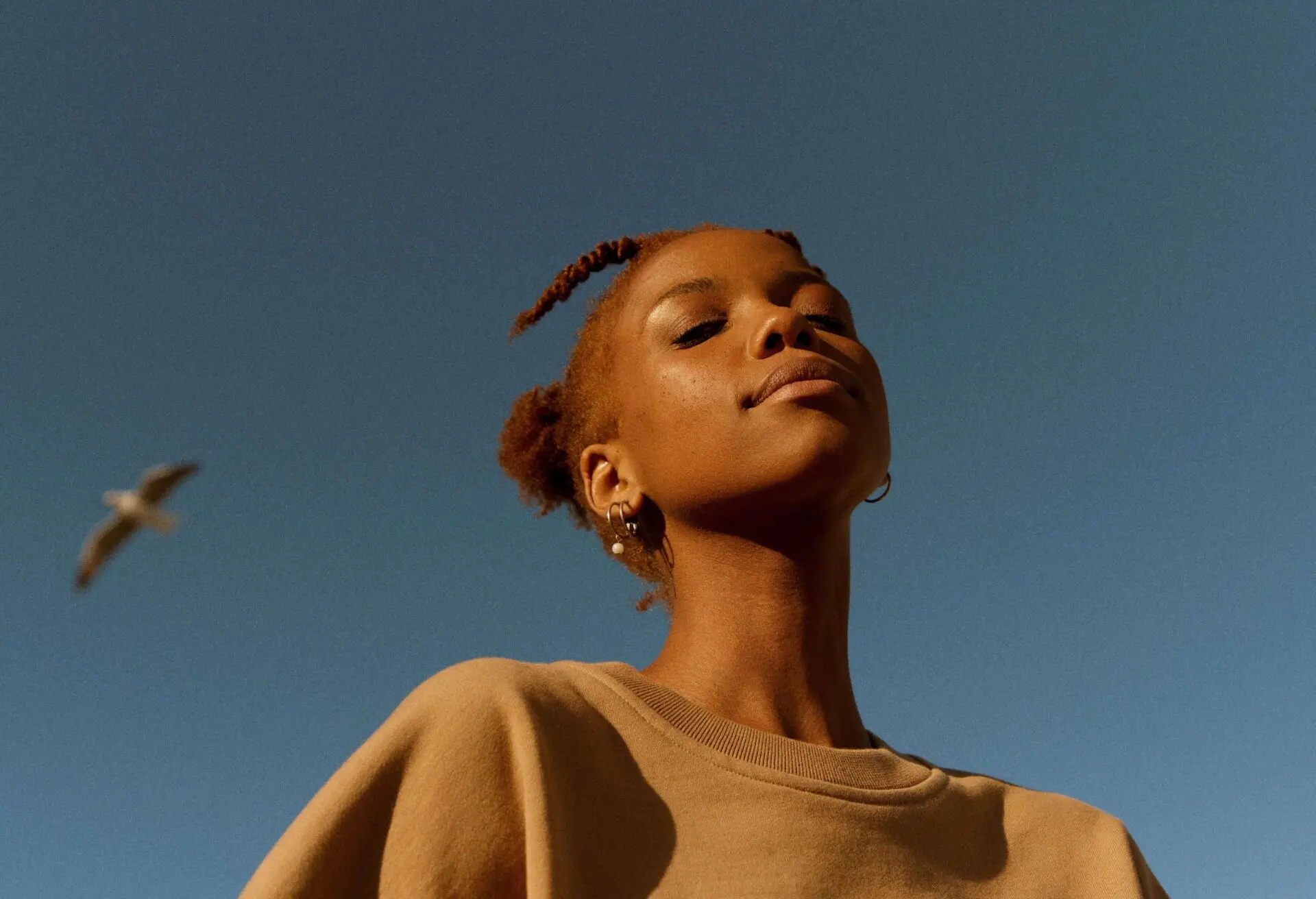 Image of a young person in front of a blue sky background.